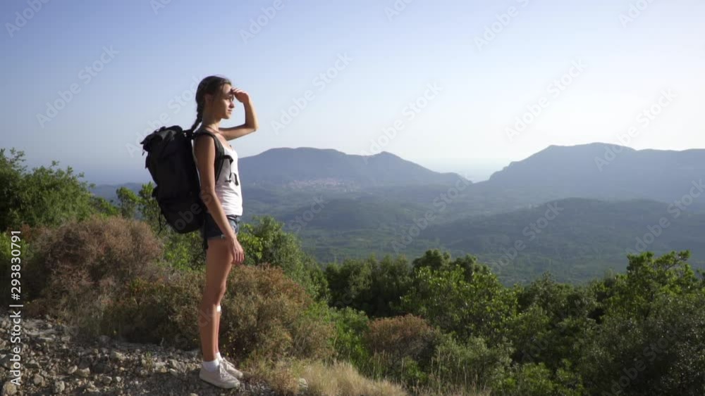 Beautiful traveler girl with backpack looks at mountainous landscape at sunset, covering her eyes with her hand from Sun. Corfu, Greece, island. Adventure time. Travelling, Tourism. Beautiful traveler girl with backpack looks at mountainous landscape at sunset, covering her eyes with her hand from Sun. Corfu, Greece, island. Adventure time. Travelling, Tourism.
