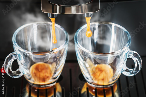 coffee beans are prepared in the coffee machine and poured into glass cups for 2 persons