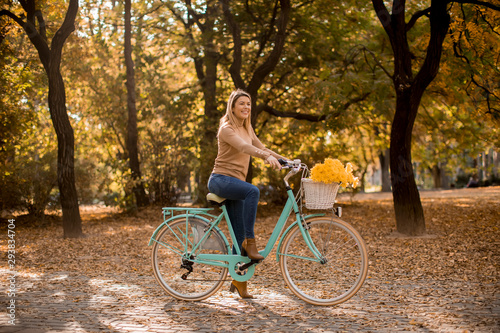 Young woman riding bicycle in golden autumn park