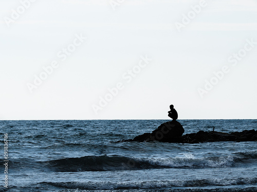 silhouette of man sitting on rock