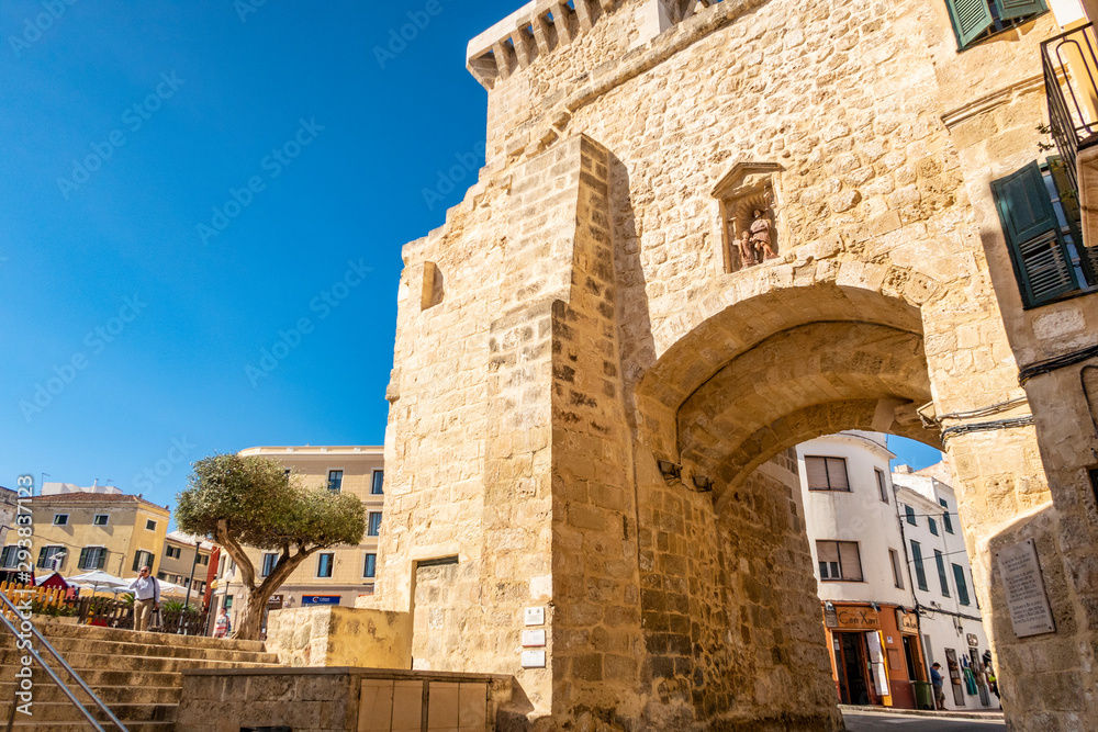 close up of the historic stone city gate in Mahon Menorca against a blue sunlit sky
