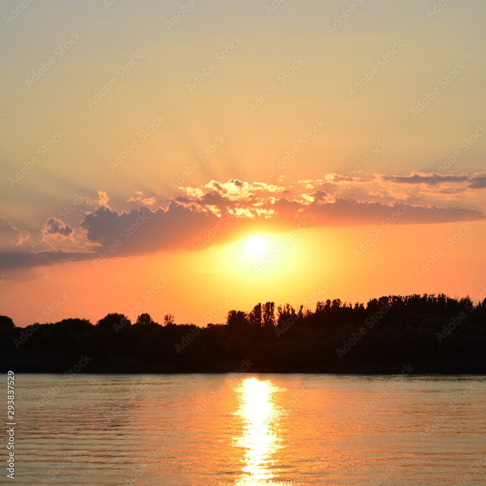Orange sunset or dawn on a cloud background. Forest and river. Country landscape in the evening.