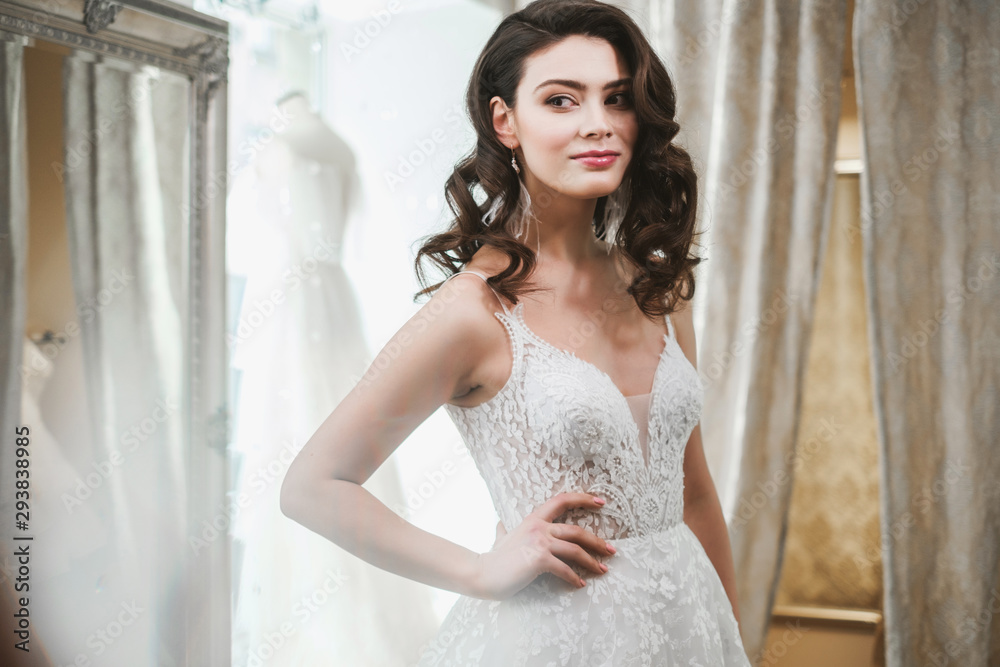 Naklejka premium Beautifu bride choosing wedding dress in a wedding salon
