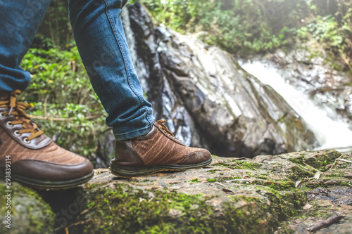Close up Traveler shoes on rock in front of waterfall. travel concept