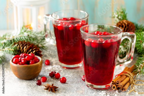 Christmas drinks. Hot winter drink with cranberries and cinnamon on a light stone table.