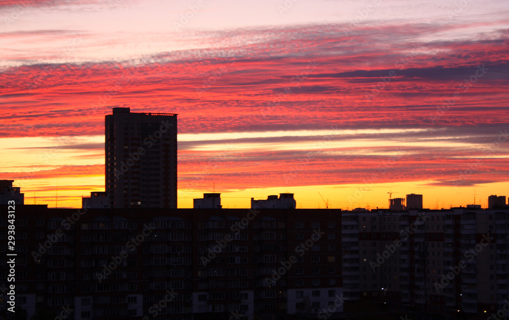 Beautiful dawn in a big city. High-rise, multi-storey buildings with many windows. The sky is pink and yellow