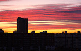 Beautiful dawn in a big city. High-rise, multi-storey buildings with many windows. The sky is pink and yellow