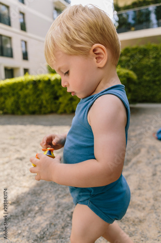 Kleinkind spielt in Sandkasten in einem Wohngebiet photo