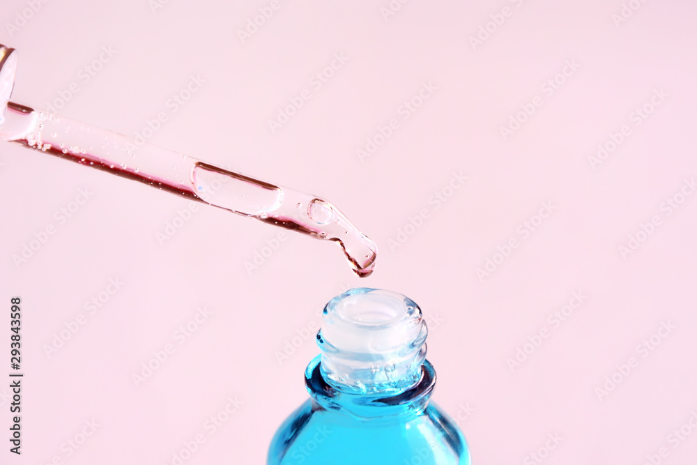 Anti aging serum in blue bottle with glass dropper on blurred pink background, selective focus. Facial liquid serum with collagen and peptides. Skincare essence for beautiful healthy skin. Soft focus - obrazy, fototapety, plakaty 