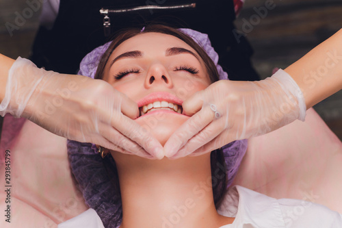 Fotografie cosmetologist makes a buccal massage of the patient's facial muscles