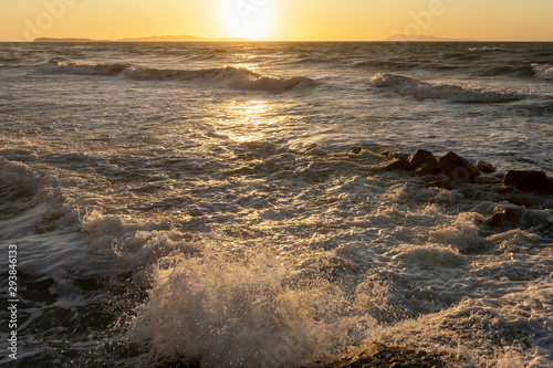 Beauty of the sea - splashing waves lighted by the sunset. Golden hour hues in semi wild unspoiled Logas Beach, Sidari, Corfu, Greece, Europa.