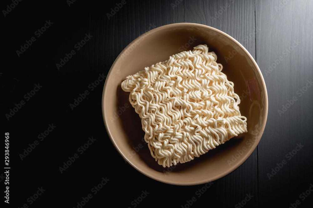 instant noodles in bowl on wooden table dark background which main ingredient from wheat, top view close up with copy space