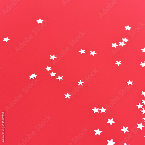 Silver stars confetti on a red background.