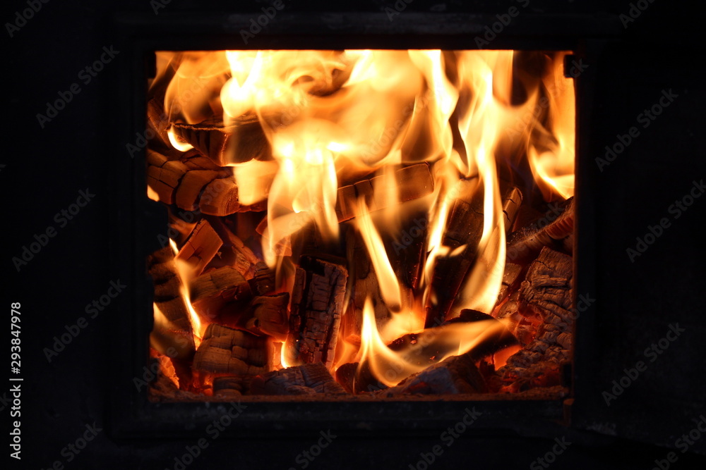 firewood burns in a bright flame in an iron stove