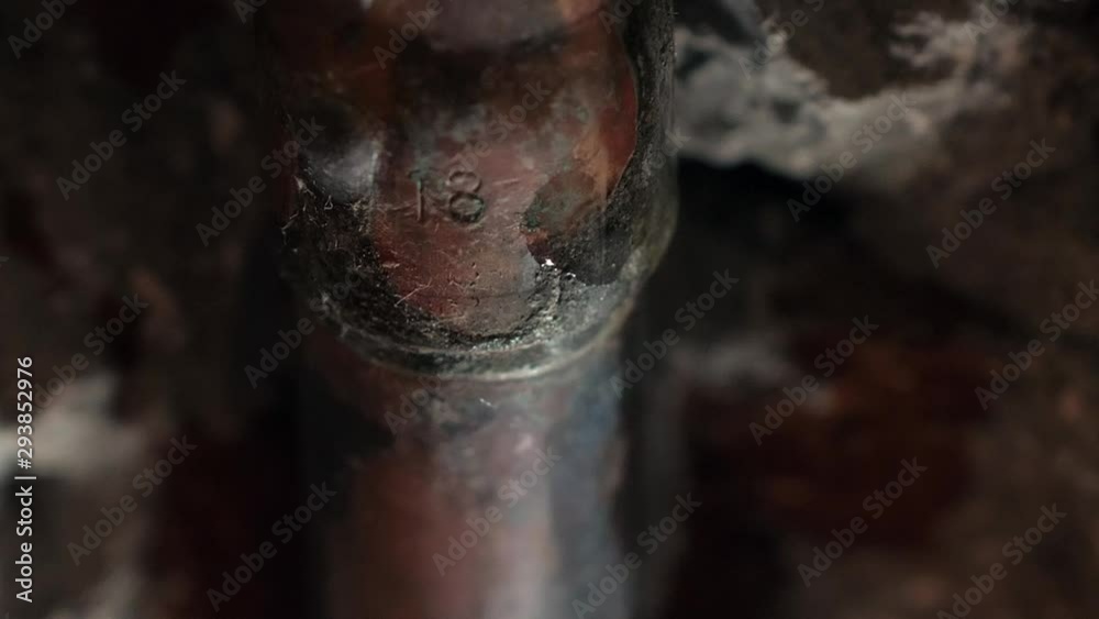 Water drains from copper tubes in the wall of the bathroom; close up shot.