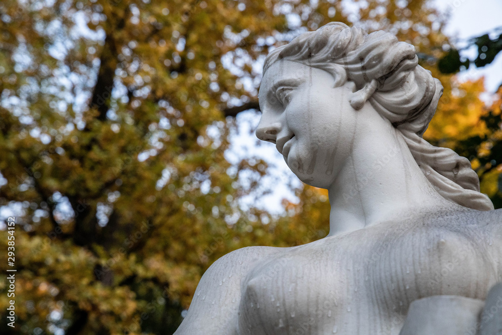 Statue in the autumn park, in the rain, wet, on the background of autumn leaves