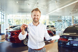 A car dealer holds keys in his hand in a showroom.
