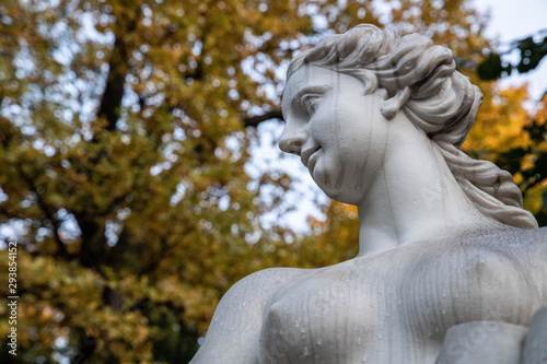 Statue in the autumn park, in the rain, wet, on the background of autumn leaves