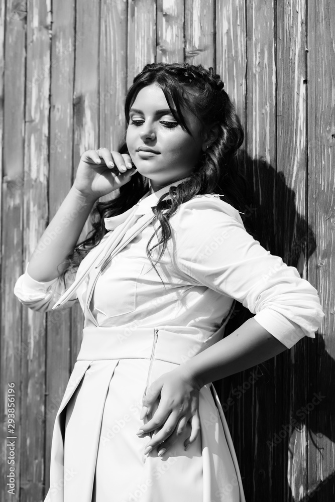 Teen girl wearing student uniform, her smiling happy on a wooden wall background. Young girl, autumn mood. Pretty girl with hair style and make up. Fashion, beauty, health. Black and white Teen girl wearing student uniform, her smiling happy on a wooden wall background. Young girl, autumn mood. Pretty girl with hair style and make up. Fashion, beauty, health. Black and white