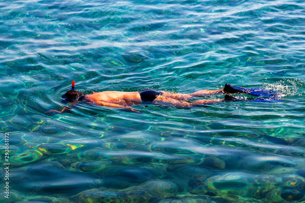 Man snorkeling with camera in hand in the sea with transparent water