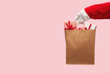 Santa Claus hand holding brown shopping bag with gift boxes