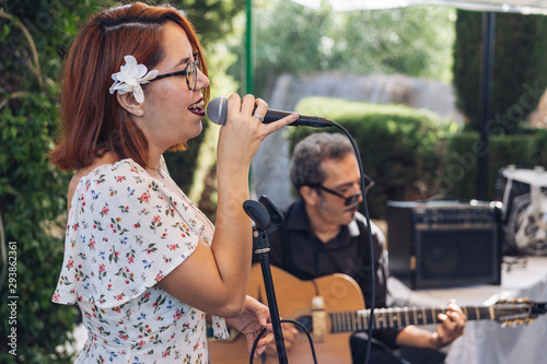 female singer on stage with a guitarist behind 