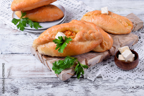 Rasstegai pie of yeast dough with meat filling on white wooden table. Traditional meal of Russian cuisine photo