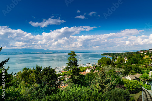 Top view of the green coast and the port of Thonon les Bains, boats, Lake Geneva, and the blue sky with clouds. © mimpki
