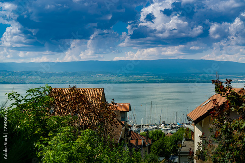 Top view of the green coast and the port of Thonon les Bains, boats, Lake Geneva, and the blue sky with clouds.