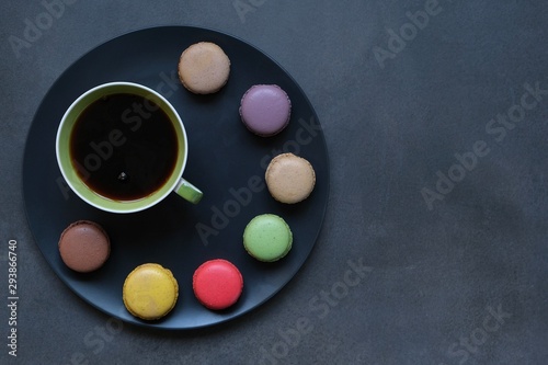 Cup of coffee and colored macaroons on a dark background. Coffee mood 