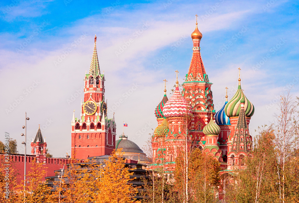 View of the Spasskaya Tower, the Moscow Kremlin and St. Basil's Cathedral from autumnal Zaryadie park. Architecture and sights of Moscow. - obrazy, fototapety, plakaty 