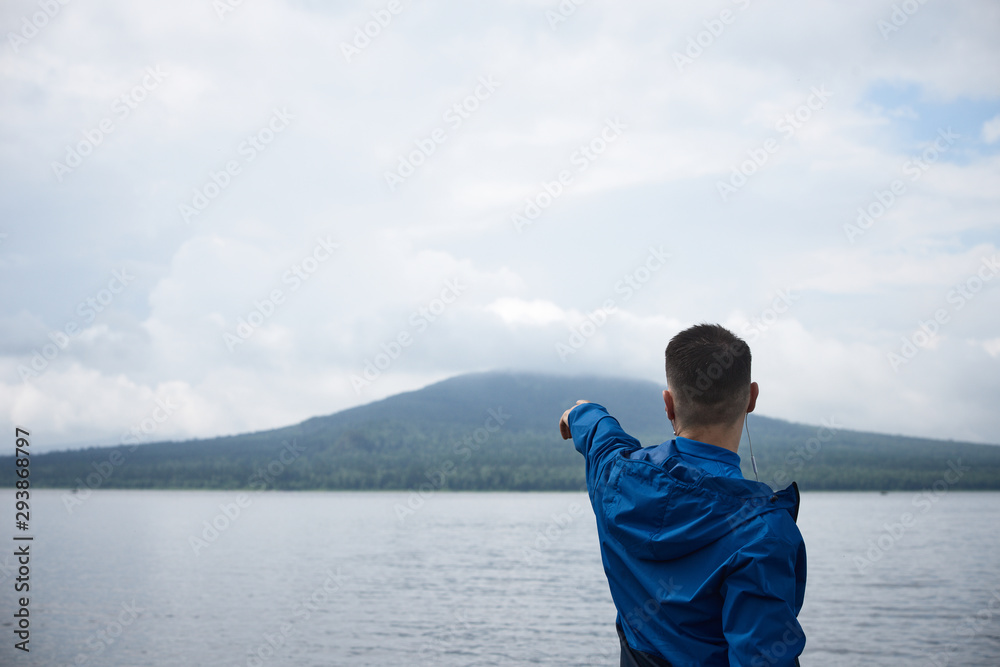 Sportsman in blue rain coat pointing at scenic view outdoor Sportsman in blue rain coat pointing at scenic view outdoor