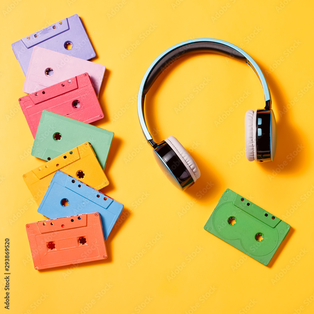 Fototapeta premium Painted audio cassettes on bright multicolor background, copy space, top view. Retro musical background