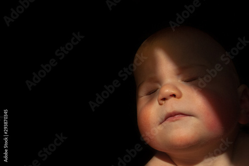 baby boy blinking into the sun with dark background