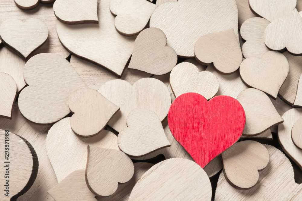 One wooden painted red heart among many colorless wooden hearts One wooden painted red heart among many colorless wooden hearts
