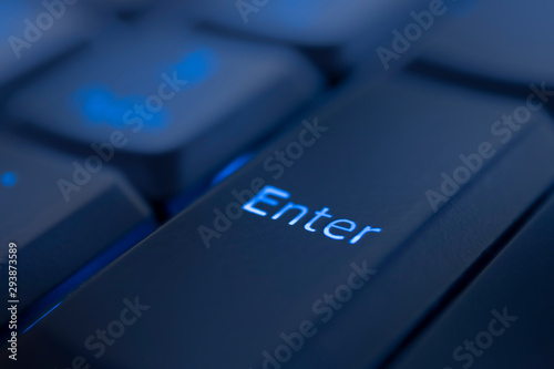 Enter key illuminated by blue LED light. Close-up of computer keyboard.