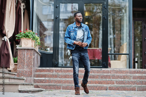 Young attractive serious african american man model. Modern handsome guy in jeans jacket standing on urban city street.