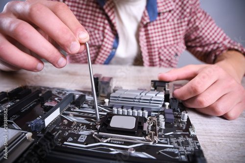Man repairing broken computer, video card,memory RAM, cooler, processor,hard drive. Young repairer working with screwdriver in service center.teenager