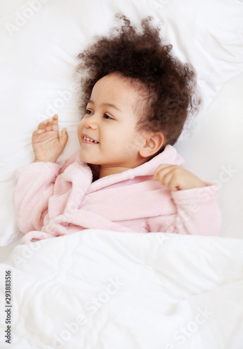 Cute little girl lying in cosy bed