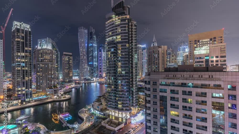 Aerial panoramic view of Dubai Marina residential and office skyscrapers with waterfront night timelapse. Floating boats and yachts Aerial panoramic view of Dubai Marina residential and office skyscrapers with waterfront night timelapse. Floating boats and yachts