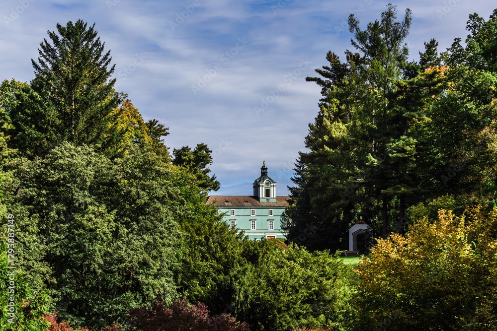 Dacice, Czech Republic - September 29 2019: Distant view of a state-owned castle Dacice from park through green trees. Sunny autumn day with blue sky and white clouds. Dacice, Czech Republic - September 29 2019: Distant view of a state-owned castle Dacice from park through green trees. Sunny autumn day with blue sky and white clouds.
