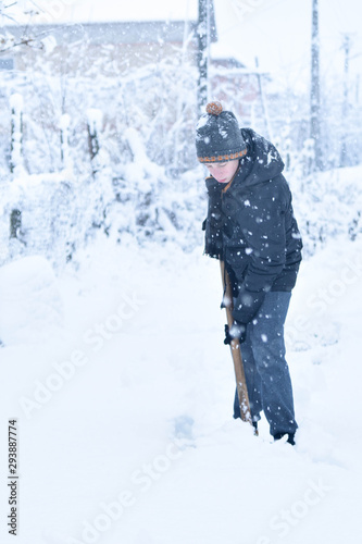  Teenager removing snow with a shovel in the winter