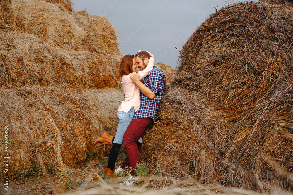 Loving couple man and woman cuddling in haystacks. Loving couple man and woman cuddling in haystacks.