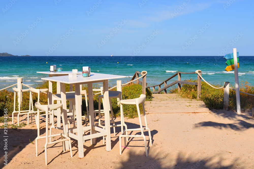 Table with chairs in a cafe overlooking the Muro beach (Playa de Muro) in Mallorca. Spain