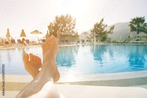 Female legs on the background of the pool on a summer day.