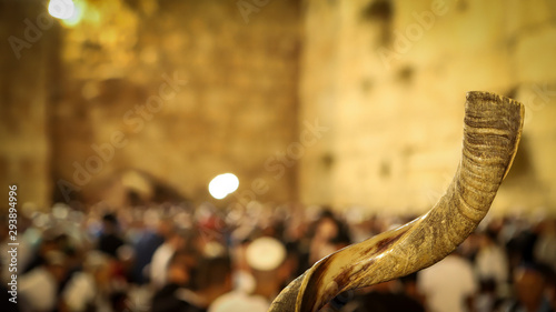 Shofar and in the background religious people pray at the Western Wall in the Holy City of Jerusalem in Israel photo