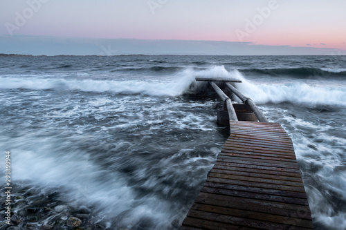 Waves crash over a broken pier in the ocean
