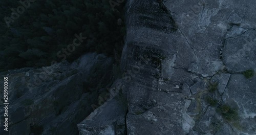 Aerial drone flight over running man on rock cliff at Yosemite National Park, 4k photo