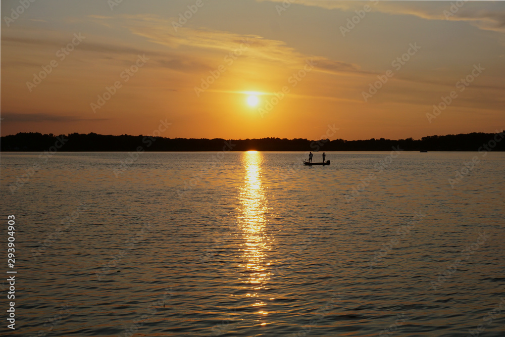 Fishing from a boat on a lake at sunset