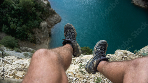 legs of a boy sitting on a cliff to a swamp photo